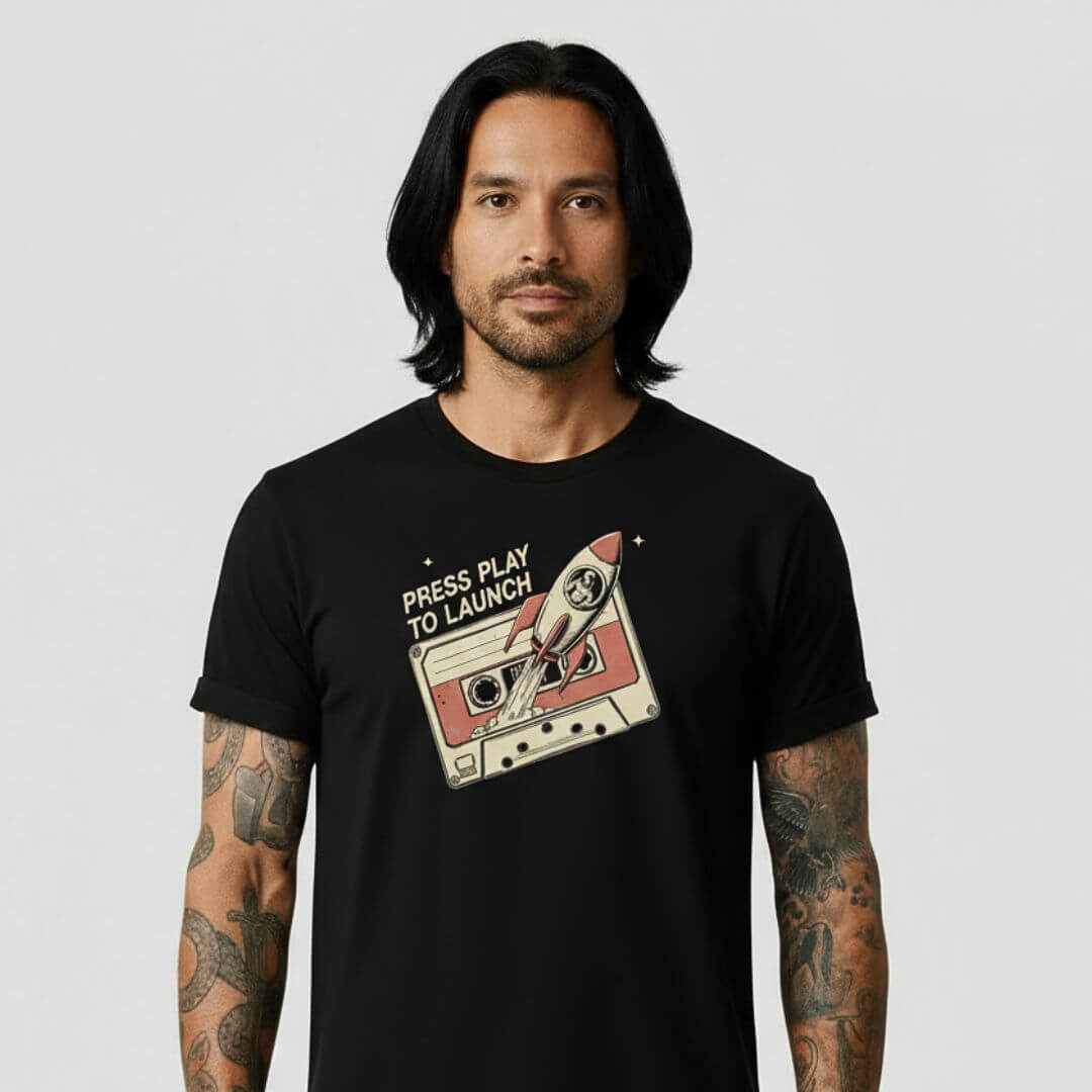 Man wearing a black t-shirt with a graphic design of a cassette tape and text on a plain background